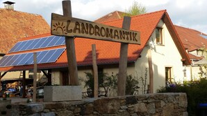 Rakennuksessa on kyltti, jossa lukee ”LANDROMANTIK”, ja sen katolla on aurinkopaneeleja.