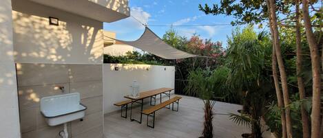 A patio with a table and chairs, a small sink, and a power outlet.