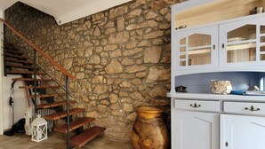 Un escalier avec des marches en bois et des rampes en métal, adossé à un mur de pierre.