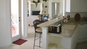 A spacious kitchen with a central island, a dining area with a chair, and a living room with a sofa. - Dream villa in top location on the wide canal & large pool area with jacuzzi (Cape Coral)