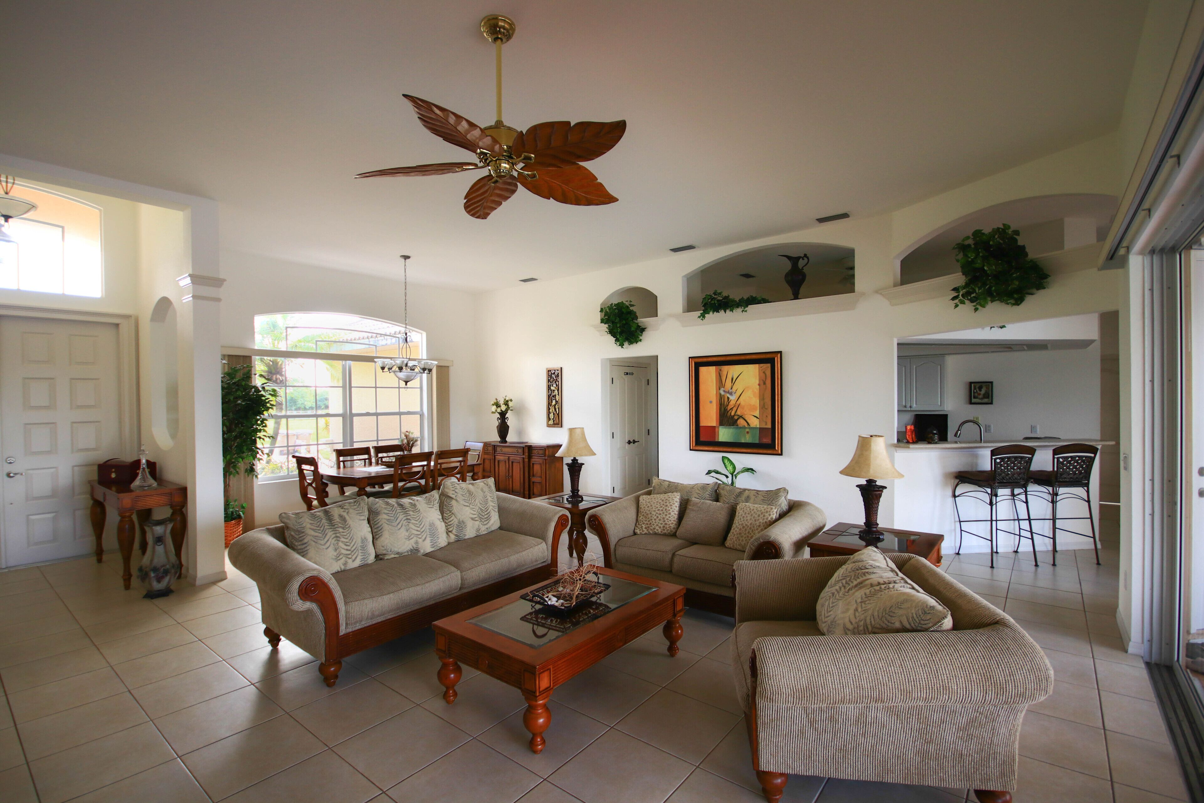 A spacious living room with a ceiling fan, two sofas, a coffee table, and a dining area with chairs and a table.