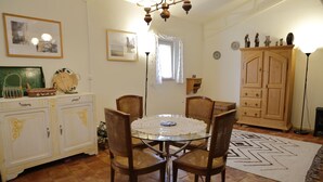 Een eetruimte met een ronde tafel, vier stoelen, een kroonluchter en een dressoir met lades.