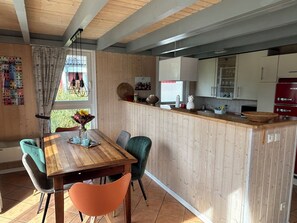 A kitchen with wooden cabinets, a wooden countertop, and a dining area with a table and chairs.