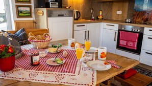 Ein Frühstücksbuffet mit kariertem Tischläufer, einem Brotkorb, einer Obstschale und einer Kaffeemaschine.