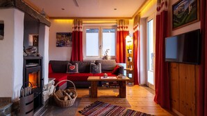 Un salon chaleureux avec une cheminée, des rideaux rouges et un téléviseur.
