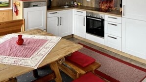Une cuisine moderne avec des meubles blancs, une table à manger en bois et un tapis rouge.