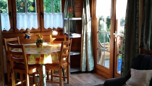 L’intérieur d’un chalet en bois comprend un coin repas, un canapé et de grandes fenêtres.