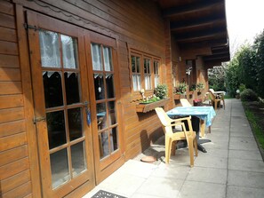 A wooden building with large windows and a patio area with tables and chairs. - Vacation home North Sea, m. Dog / child -Cuxhaven- Sahlenburg umz. Garden, sandy beach (Cuxhaven)