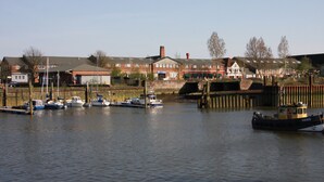 Un port de plaisance avec plusieurs bateaux amarrés, un pont en arrière-plan et des immeubles résidentiels à proximité.