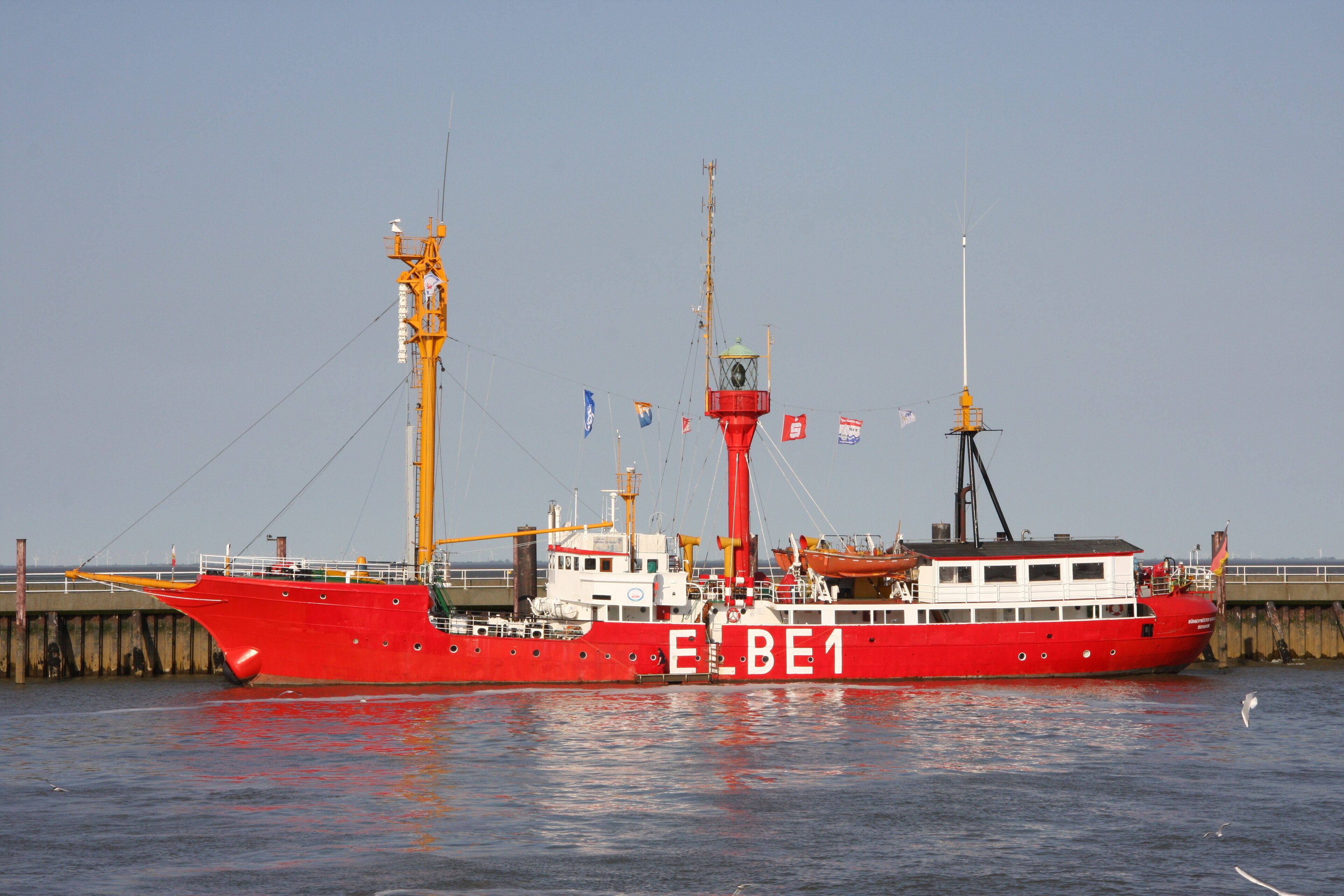 Un ferry rojo llamado E.L.B.E.1 atracado en un muelle, con un cielo despejado.
