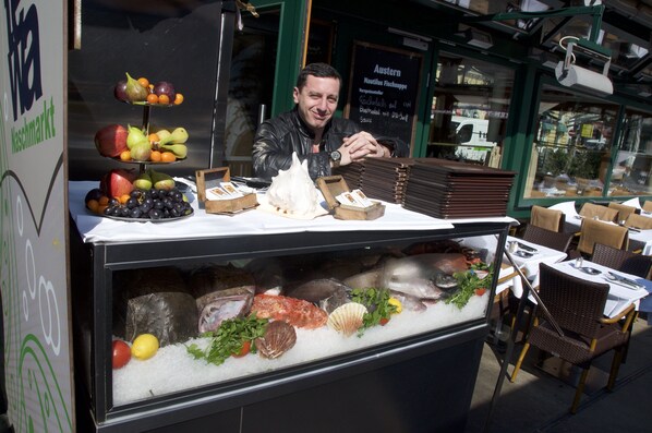 A seafood display at a market stall with various fish, seafood, and fruits.