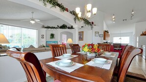 Comedor con una mesa de madera preparada para cuatro personas, rodeada de sillas de madera.