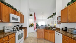 Una cocina con armarios de madera, microondas, estufa y lavavajillas.