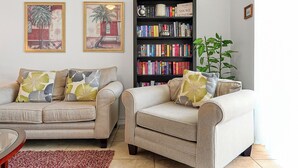 Una sala de estar con dos sofás, una estantería y una planta en maceta.