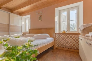Un dormitorio con una cama de madera, una ventana con vistas y una mesita de noche con una lámpara.