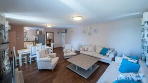 Ein Wohnzimmer mit Sofa, Sesseln, einem Couchtisch und einem Essbereich mit Tisch und Stühlen.