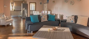 Una sala de estar con un sofá gris, una mesa de centro y una zona de comedor al fondo.