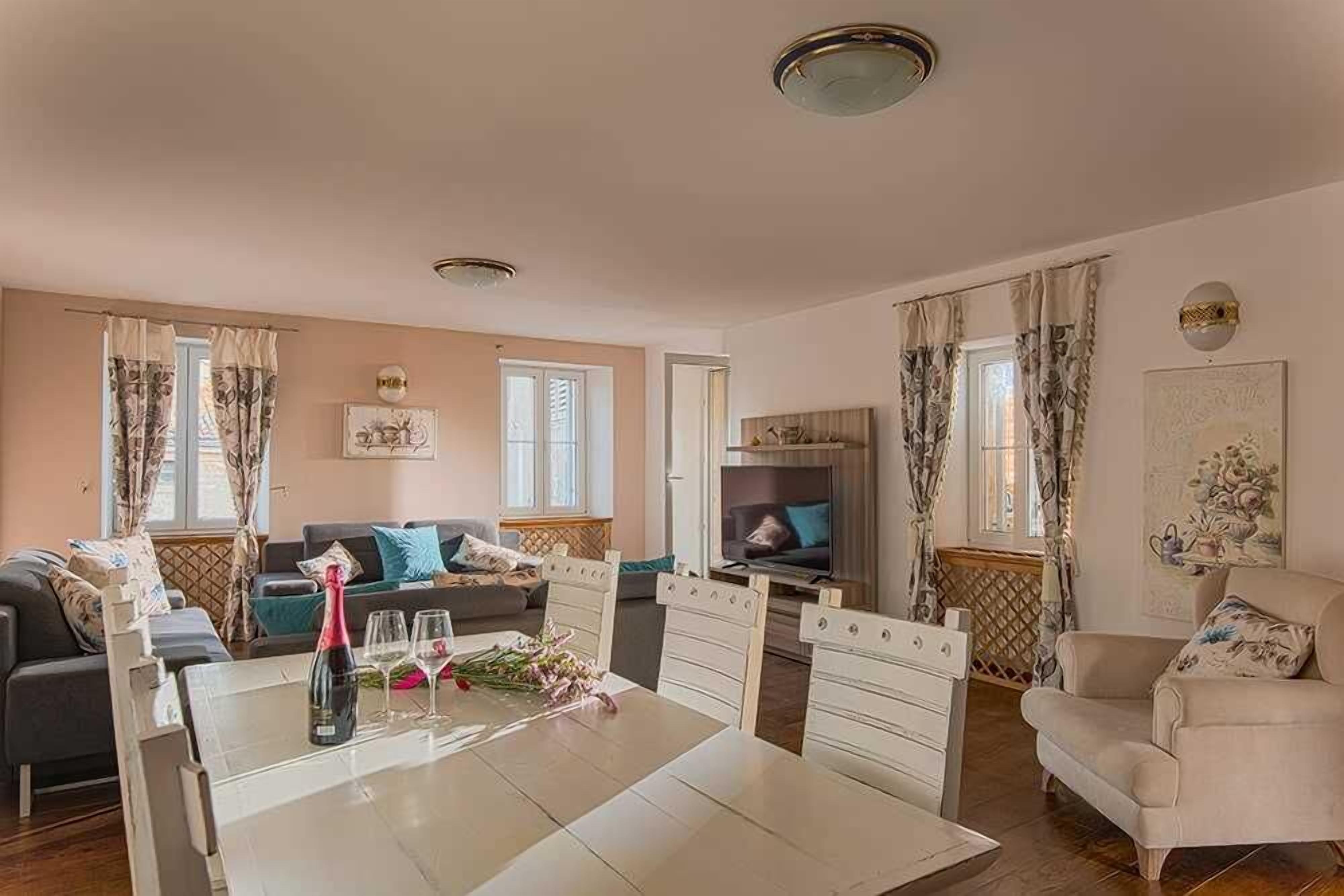 A spacious living room with a dining table, sofas, a TV, and a fireplace.