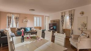 Ein geräumiges Wohnzimmer mit Esstisch, Sofas, Fernseher und Kamin.