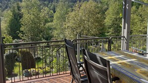 Ein Balkon mit Tisch und Stühlen, mit Blick auf ein bewaldetes Gebiet.