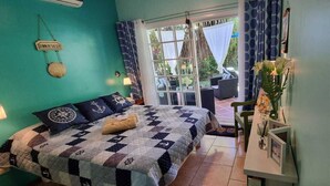 A bedroom with a bed, a nightstand, a window with curtains, and a view of the outdoors.