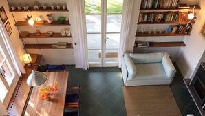 Een ruime woonkamer met een houten eettafel, een bank en een boekenkast vol boeken.
