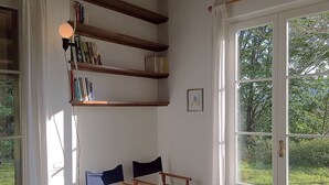 Een kamer met een groot raam, houten planken en twee blauwe stoelen.