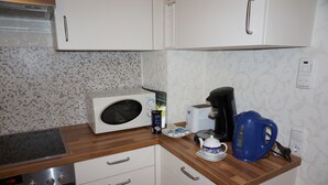 Eine Küche mit Mikrowelle, Toaster, Wasserkocher und Kaffeemaschine auf der Arbeitsfläche.