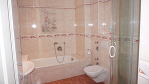 Ein Badezimmer mit Badewanne, Toilette und einer Duschkabine.