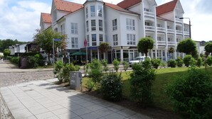 A large, multi-story building with a red-tiled roof and white walls, featuring a central tower and multiple balconies.