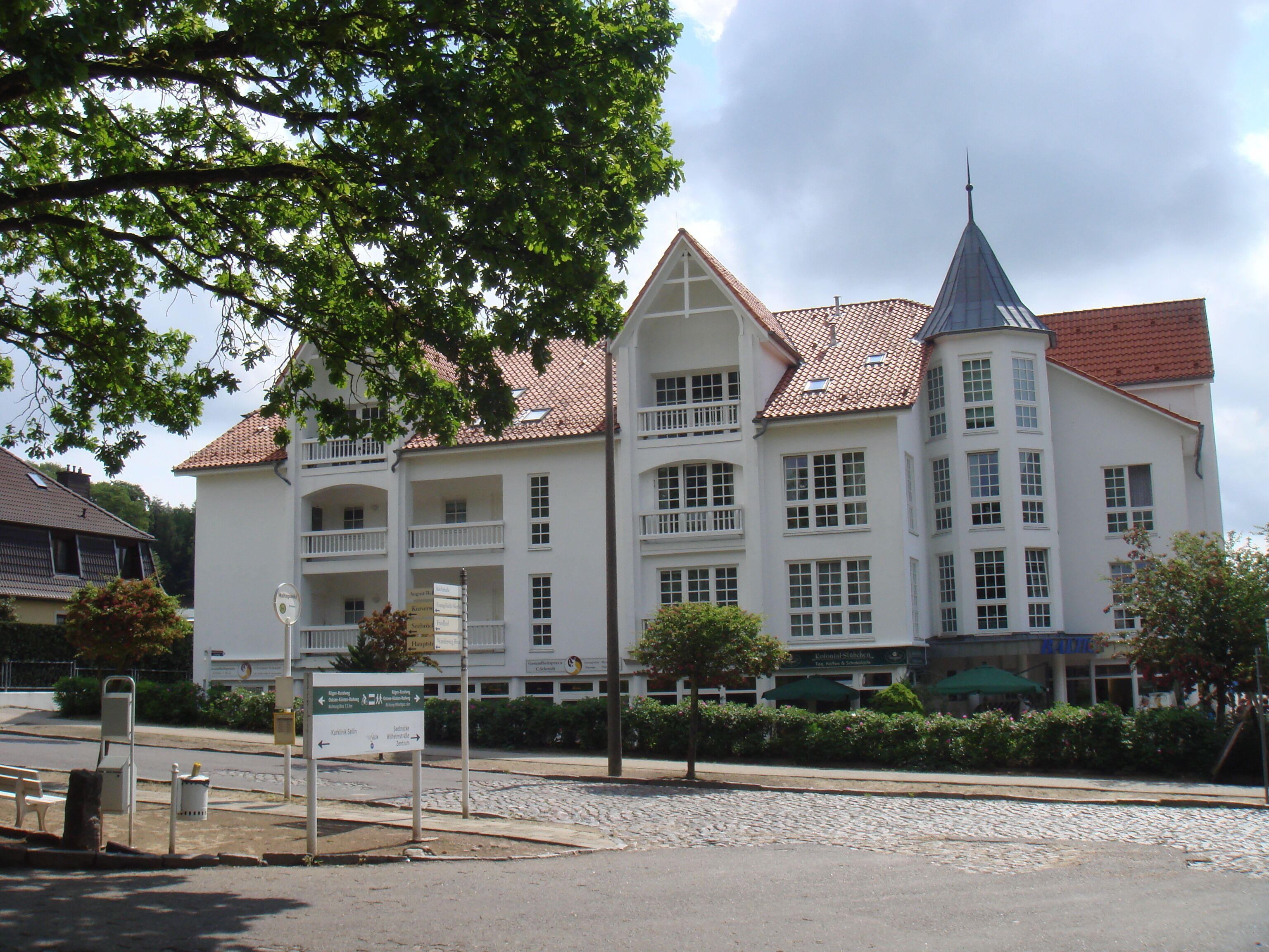 A large, white building with multiple balconies and a red-tiled roof.