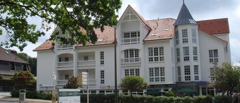 A large, white building with multiple balconies and a red-tiled roof.