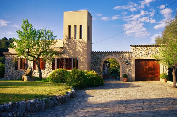 Un edificio de piedra con una torre central, una entrada en arco y un camino de entrada pavimentado.