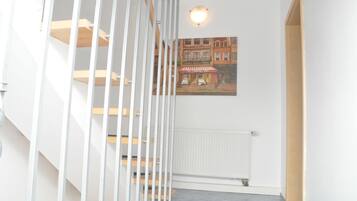 A staircase with white railings and wooden steps, a white radiator, and a framed picture of a street scene on the wall.