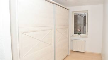 A room with a sliding door, a window with a view of a brick wall, and a radiator below the window.