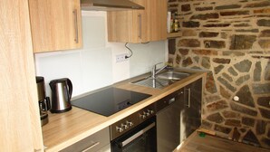 Eine Küche mit Holzausstattung, einer Steinwand, einem Edelstahl-Spülbecken und einem eingebauten Backofen.