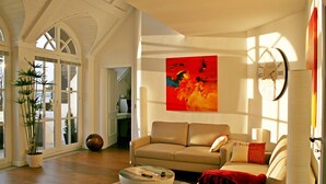 Un salon spacieux avec un canapé beige, une table basse et un grand tableau abstrait.