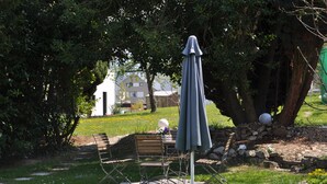 Een tuin met een bank, een tafel en een parasol.