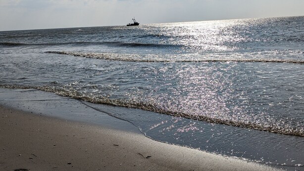 A beach with waves and a boat in the distance. - Top Vacation Villa, 120 sqm, Near the Beach, Quiet, 3 Bedrooms, 2 Bathrooms, Fireplace, Wi-Fi (Julianadorp aan Zee)