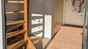 A wooden staircase leading to a landing with a small decorative wall piece and a door with a unique window design. - Top Vacation Villa, 120 sqm, Near the Beach, Quiet, 3 Bedrooms, 2 Bathrooms, Fireplace, Wi-Fi (Julianadorp aan Zee)