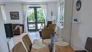 A spacious living room with a wooden dining table, wicker chairs, and a hanging light fixture. - Top Vacation Villa, 120 sqm, Near the Beach, Quiet, 3 Bedrooms, 2 Bathrooms, Fireplace, Wi-Fi (Julianadorp aan Zee)