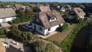 A residential area with houses featuring thatched roofs and a small body of water nearby. - Top Vacation Villa, 120 sqm, Near the Beach, Quiet, 3 Bedrooms, 2 Bathrooms, Fireplace, Wi-Fi (Julianadorp aan Zee)
