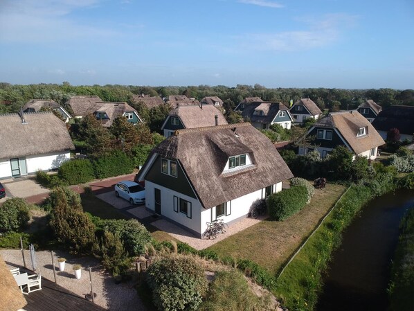 A residential area with houses featuring thatched roofs and a small body of water nearby. - Top Vacation Villa, 120 sqm, Near the Beach, Quiet, 3 Bedrooms, 2 Bathrooms, Fireplace, Wi-Fi (Julianadorp aan Zee)