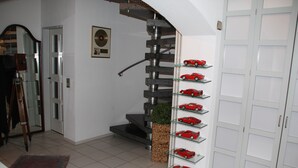 A modern interior with a spiral staircase, a glass display of toy cars, and a white door.