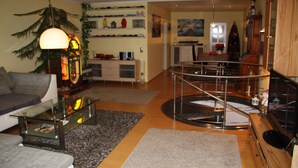 A living room with a glass coffee table, a sofa, a wooden cabinet, and a staircase leading to an upper level.
