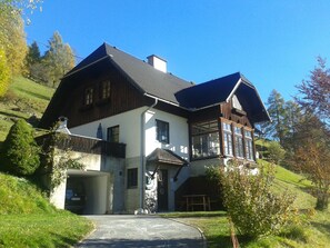 A large, two-story house with a steeply pitched roof, a garage, and a well-maintained lawn. - Suns apartment at the foot of Tockneralm at 1400m above sea level with fantastic Au (Krakau)