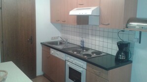 A compact kitchen with wooden cabinets, a built-in stove, a sink, and a coffee maker.
