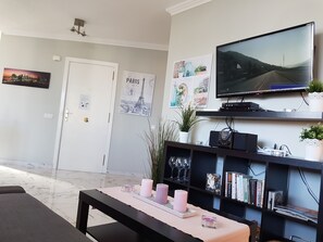 Relax in a cozy seating area with a flat-screen TV, bookshelf, and comfortable bench.