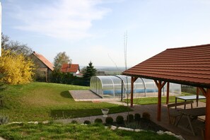 Un jardin avec une serre, un pavillon en bois et une pelouse.