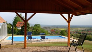 Un espace extérieur abrité comprenant une piscine, des chaises longues et une vue sur la campagne.